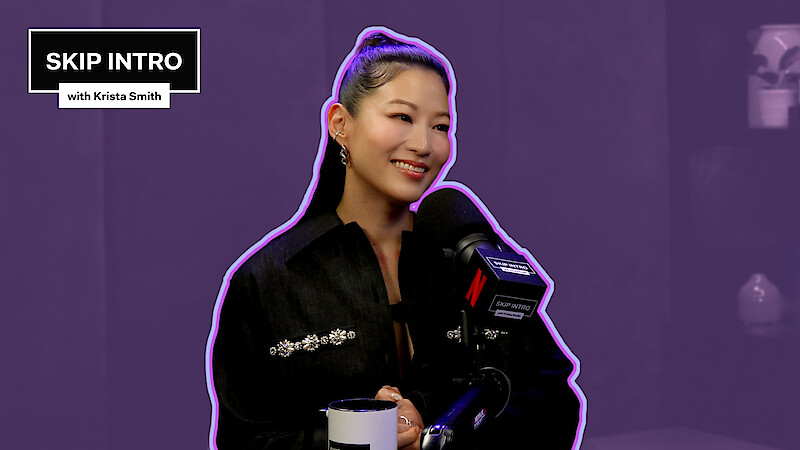 Arden Cho behind a microphone, set against a purple background.