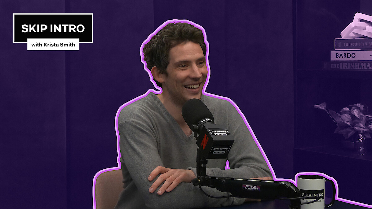 Josh O'Connor smiles while speaking into a podcast microphone in a purple studio, outlined with a neon accent, with a “Skip Intro with Krista Smith” graphic in the corner.