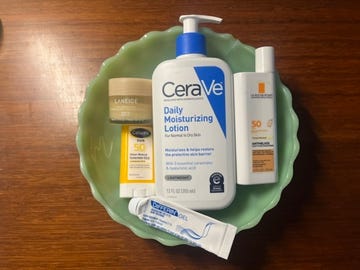 Skincare products arranged in a green dish on a wooden surface. Skincare products arranged in a green dish on a wooden surface.