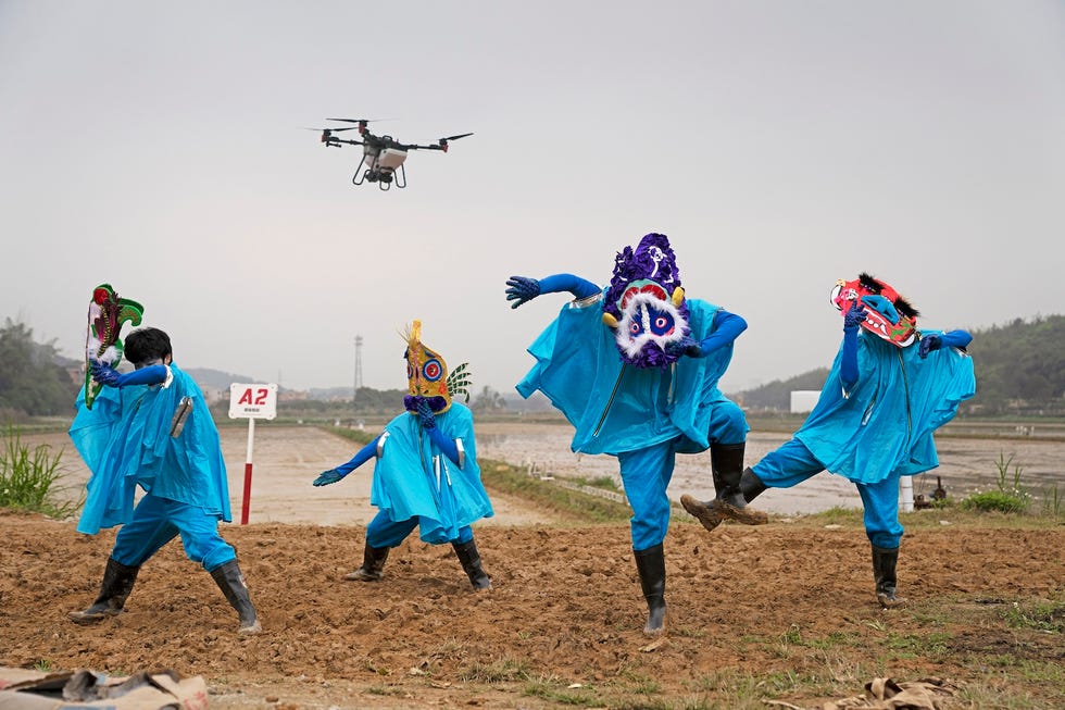 people in colorful costumes dancing with a drone flying overhead people in colorful costumes dancing with a drone flying overhead