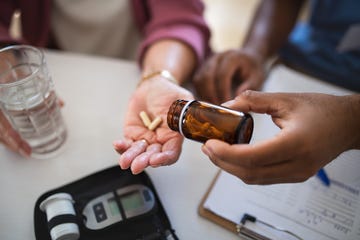 Close up of male healthcare worker or caregiver hand giving pills to senior woman indoors during home visit. Close up of male healthcare worker or caregiver hand giving pills to senior woman indoors during home visit.