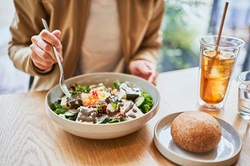 Asian woman enjoying lunch at a vegan cafe. Asian woman enjoying lunch at a vegan cafe.