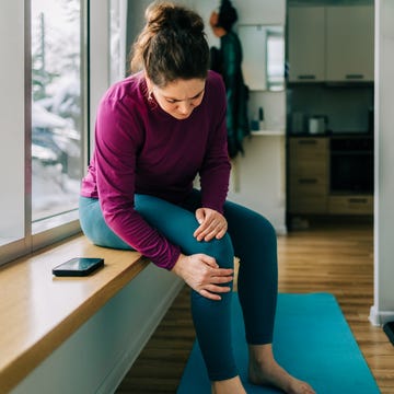 Woman suffering from knee pain at home after exercising Woman suffering from knee pain at home after exercising