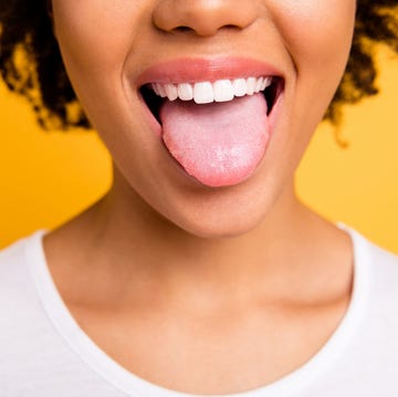 Cropped close up photo beautiful amazing she her dark skin lady beaming whitening toothy smile tongue out perfect mouth wear casual white t-shirt isolated yellow bright vibrant background swollen tongue