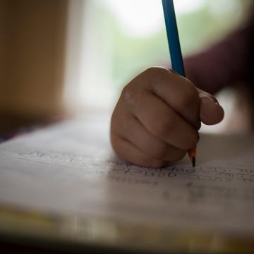 Cropped image of girl writing homework on table at home Hand writing on paper with a pencil