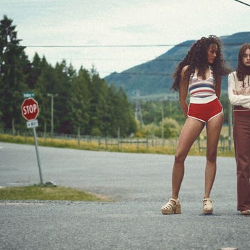 two individuals standing at a rural intersection with stop sign and mountains in background. two individuals standing at a rural intersection with stop sign and mountains in background.