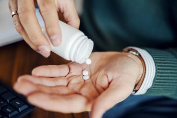 Person pouring white medication pills into hand Person pouring white medication pills into hand
