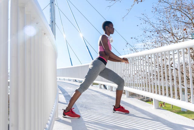 Young female athlete stretching legs while practicing on bridge during sunny day a person performing a lunge exercise on a bridge