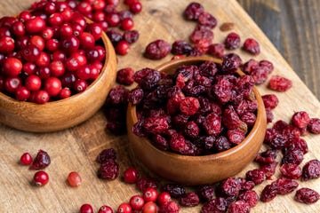 fresh cranberries in a wooden bowl on the left next to dried cranberries in a wooden bowl on the right fresh cranberries in a wooden bowl on the left next to dried cranberries in a wooden bowl on the right