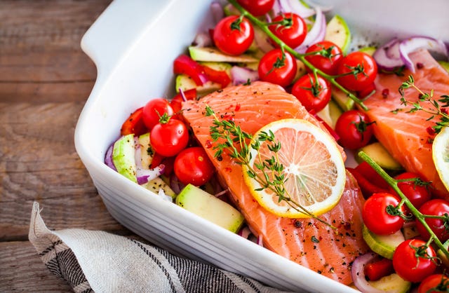Raw fresh delicious salmon and vegetables raw fresh delicious salmon, cherry tomatoes, onion, zucchini, pepper and lemon in pan, ready to cook