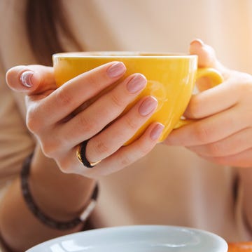 Yellow mug in the hands of a young woman. Girl holding a Cup of coffee in a cafe. Coffee break, Breakfast. The concept of power. Close up. Yellow mug in the hands of a young woman. Girl holding a Cup of coffee in a cafe. Coffee break, Breakfast. The concept of power. Close up.