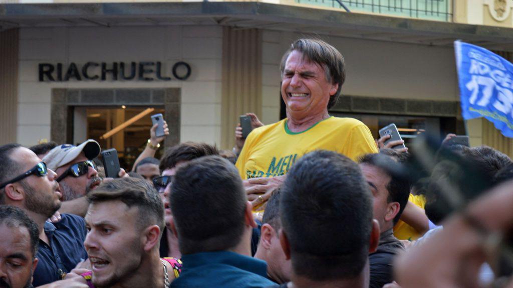 Jair Bolsonaro winces in pain after being stabbed in the stomach during a campaign rally in Juiz de Fora on September 6, 2018. He is wearing a yellow Brazil football shirt. Around him people look distraught