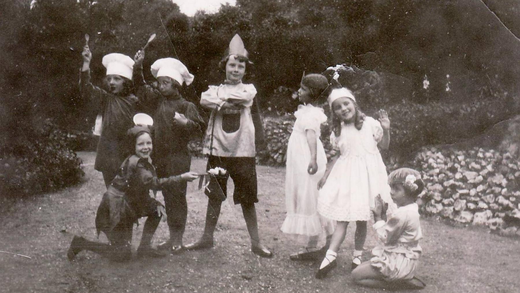 A black and white photograph of Audrey Hepburn (centre, wearing a long hat) with school friends in Elham