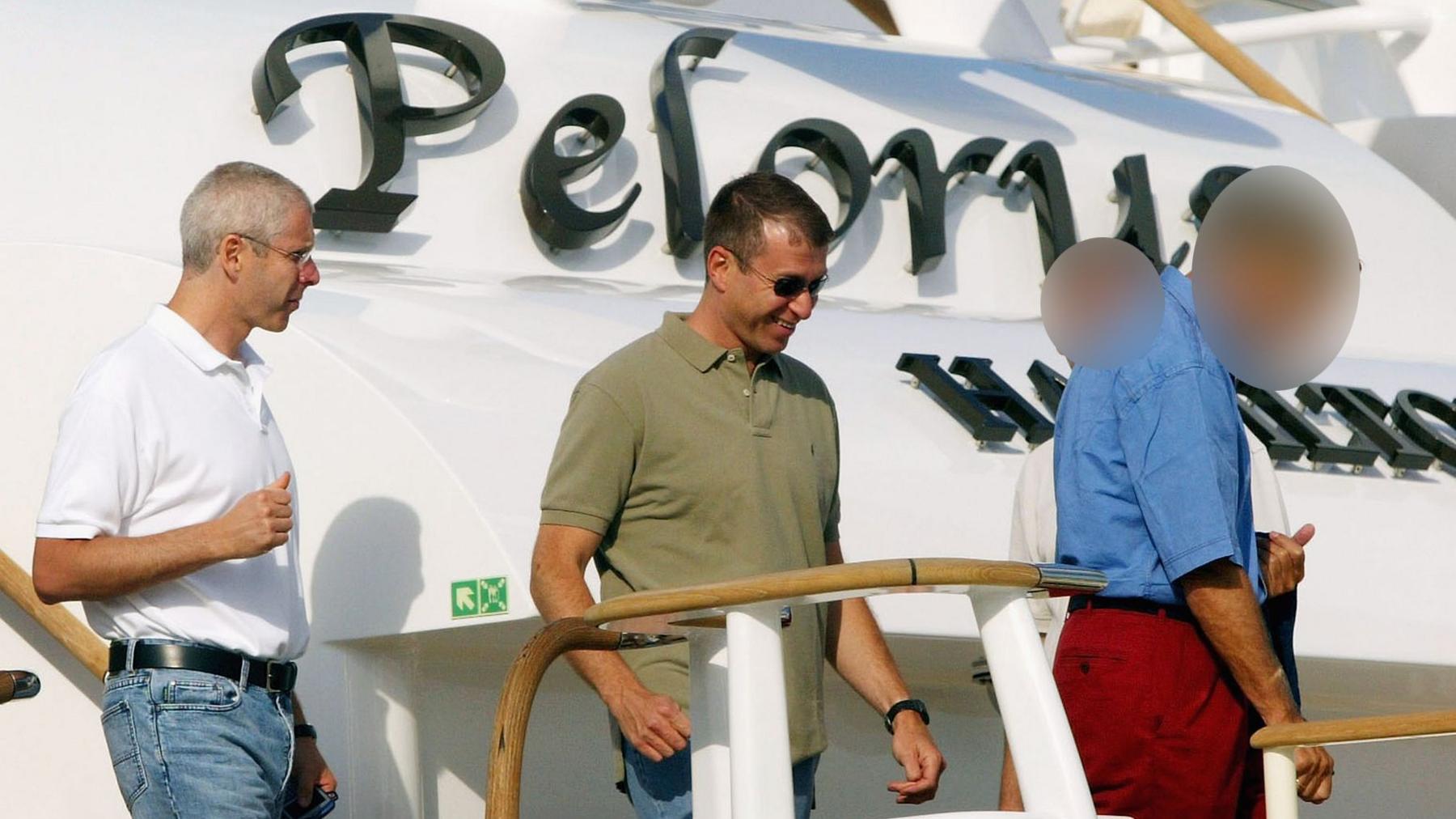 Eugene Tenenbaum (left) and Roman Abramovich (right) on board the Pelorus superyacht in 2004. The name of the boat is visible behind the two men, who are both wearing polo shirts and jeans.
