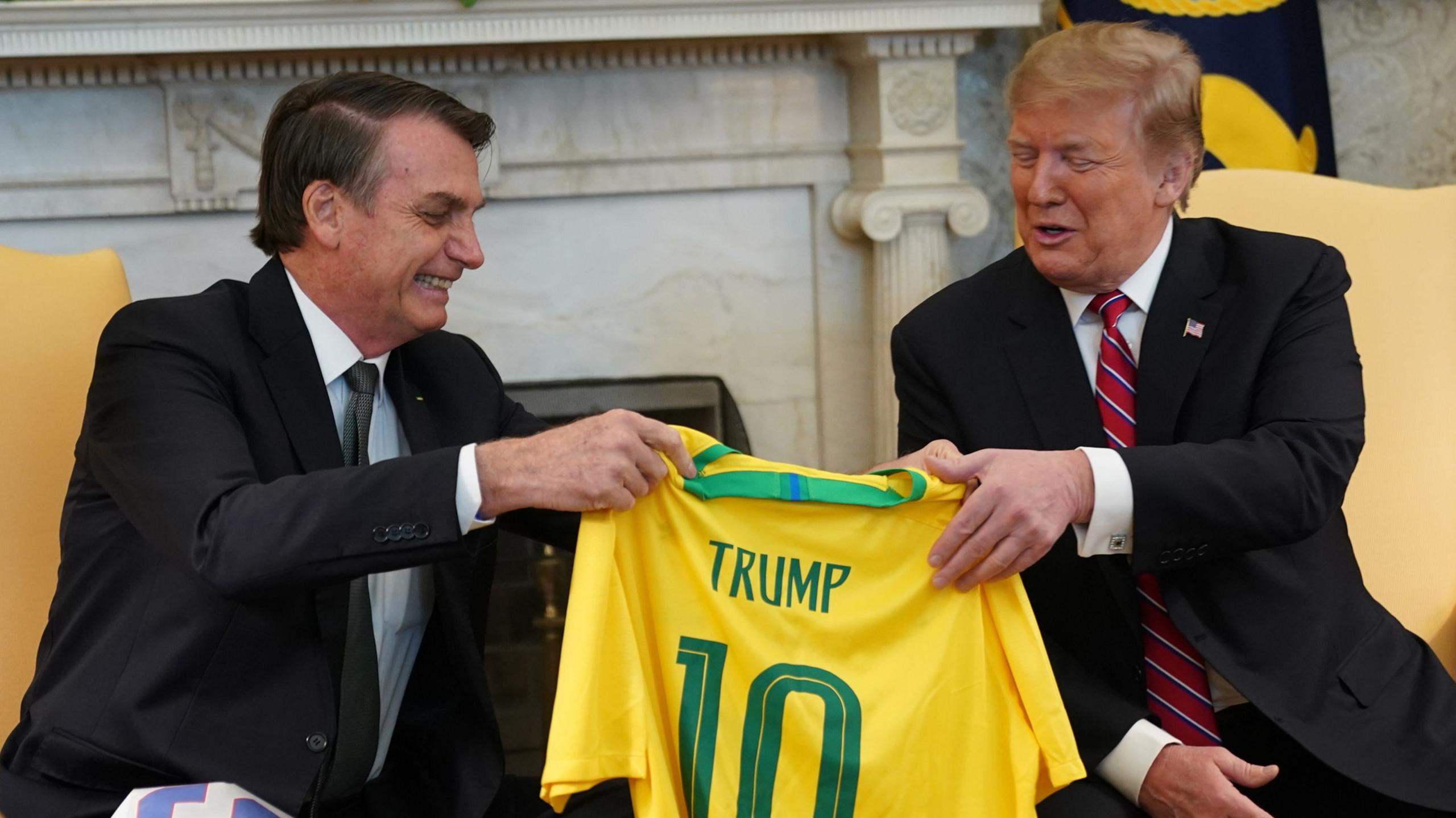 Bolsonaro hands Trump a Brazil football shirt, with Trump's name on it, in the White House.
