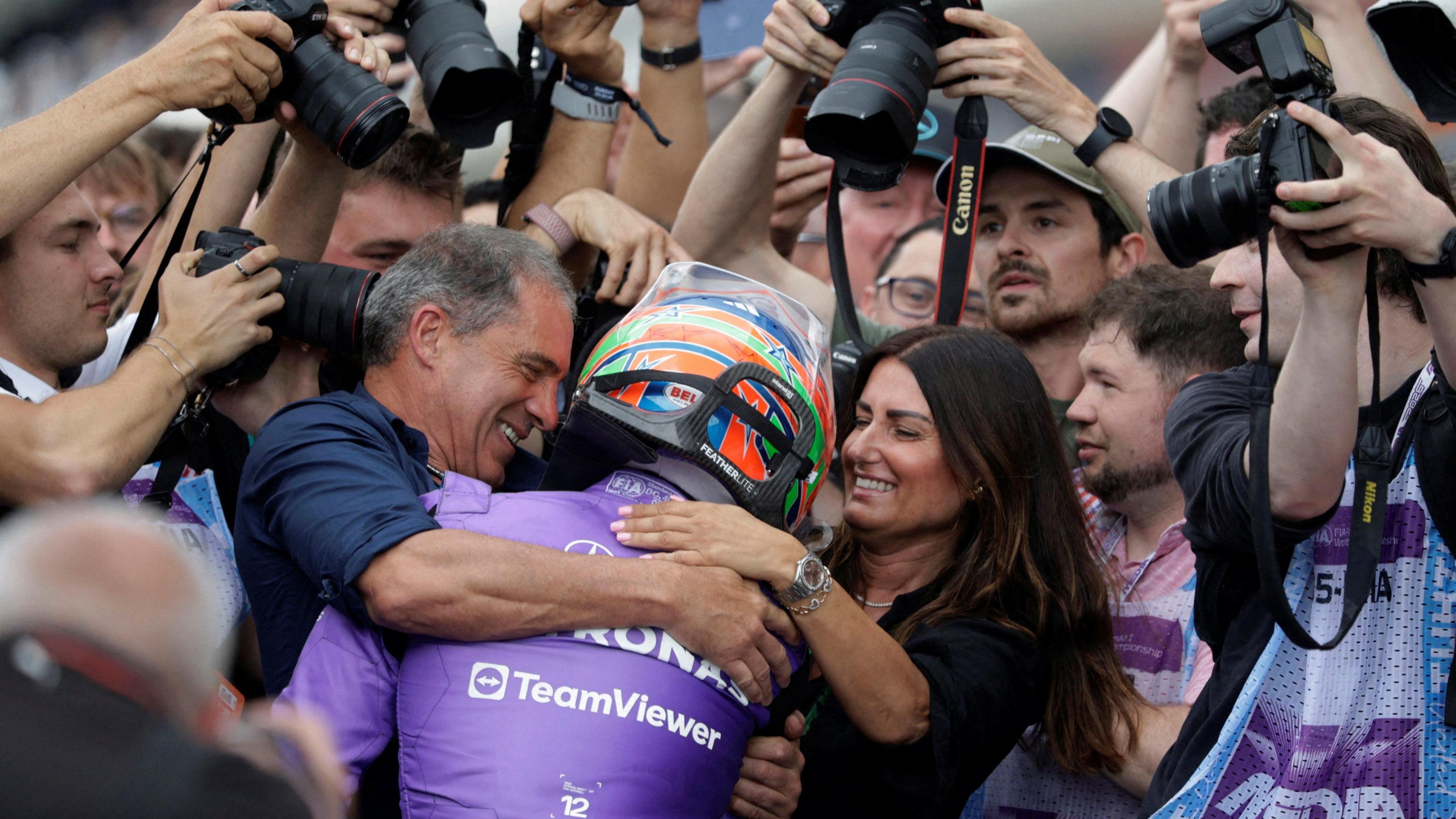 Kimi Antonelli is embraced by his mum Veronica and dad Marco while surrounded by photographers after winning the 2026 Miami Grand Prix