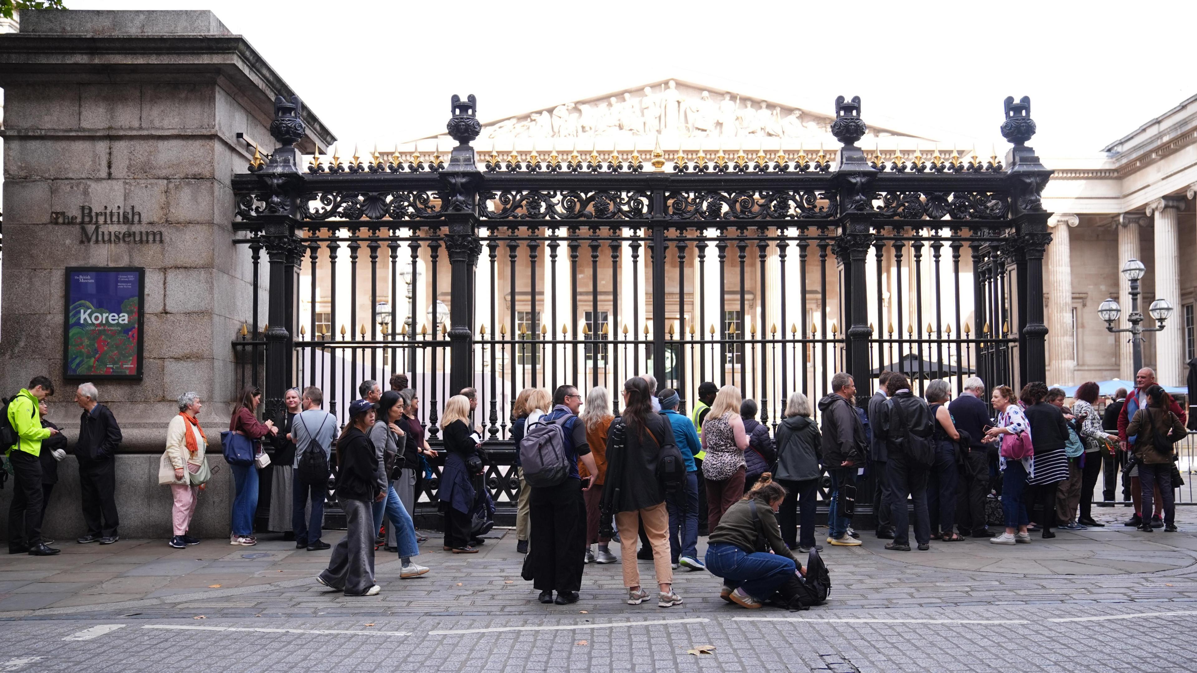 People wait in line outside the British Museum in central London as the Bayeux Tapestry exhibition opens to members of the public