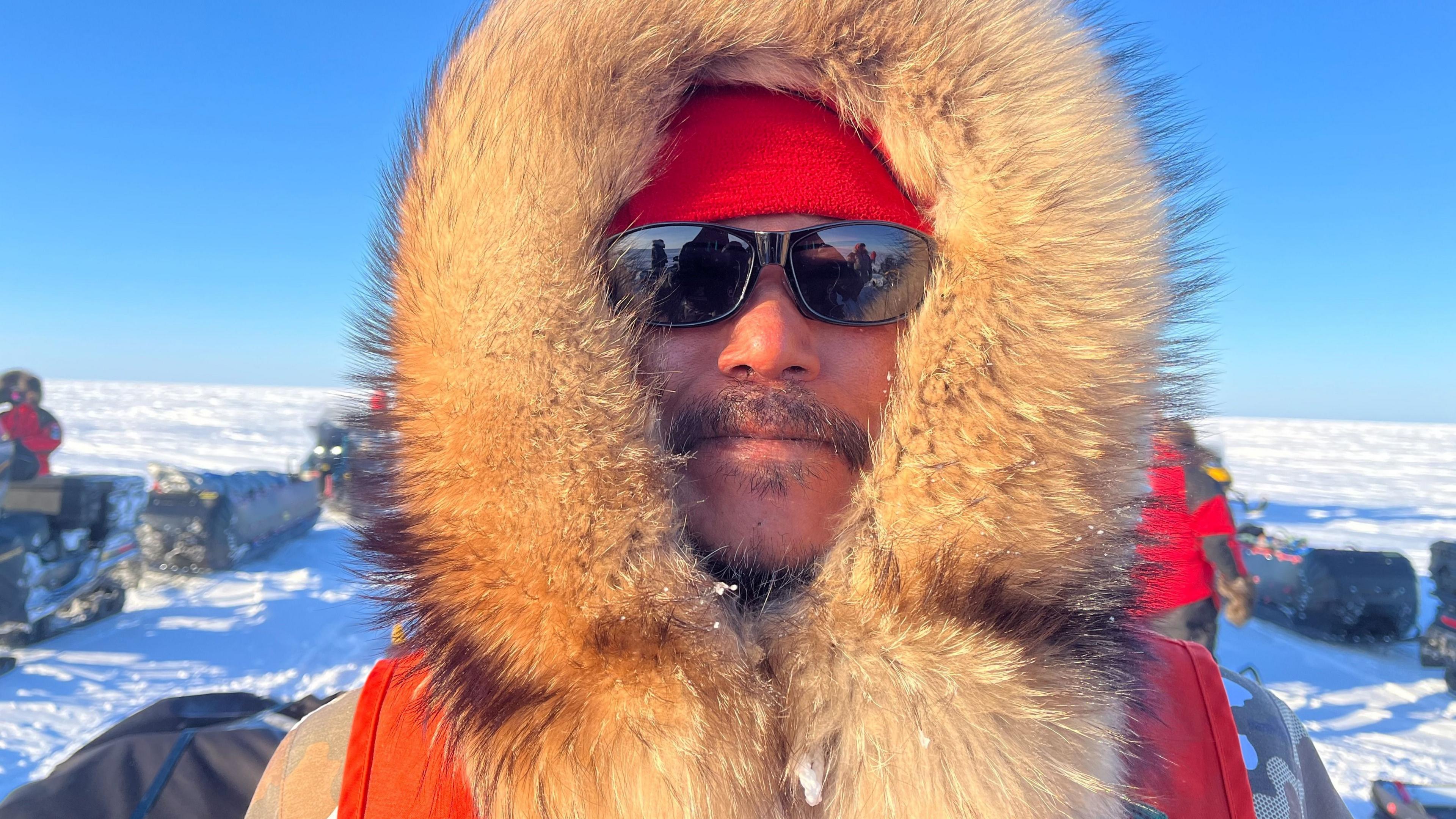 Barnie Aggark, an Inuk man, pictured wearing a hood with a thick fur trim and sunglasses