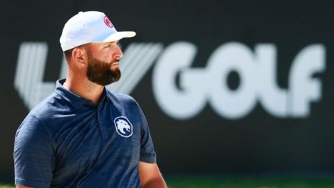 Jon Rahm in front of a LIV Golf sign