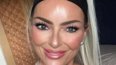Jennifer Anne Brown pictured smiling and looking at the camera. She has long blonde hair tied up and is wearning a black hairband and hoop earings.