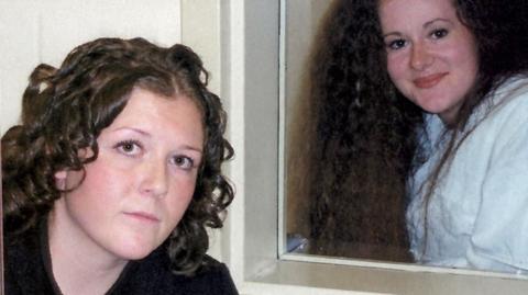 Helen roberts pictured at the forefront of the photograph, with Christ Pike behind her. The pair are separated by a glass window and both have brown curly hair and brown eyes.