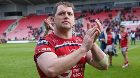 Ryan Elias in red Scarlets jersey claps the crowd