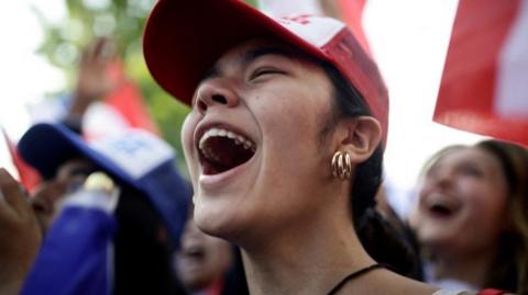 A happy young woman shouting in a crowd.