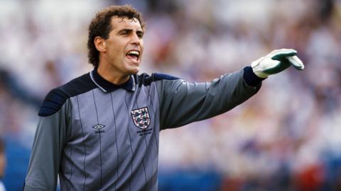 Peter Shilton is wearing an England goalkeeper's jersey and goalkeeper gloves during the 1986 World Cup match between Portugal and England.