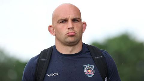Tom Christie wearing a navy Newcastle Red Bulls t-shirt with a backpack on both shoulders