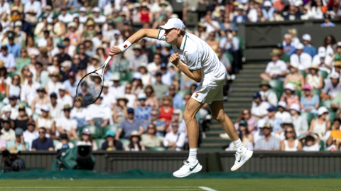 Jannick Sinner jumps to hit a shot at Wimbledon