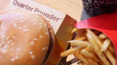 A McDonald's quarter pounder burger next to some chips in a red container