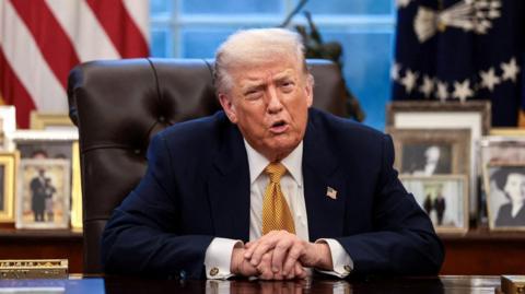 US President Donald Trump sits behind the Oval Office desk.