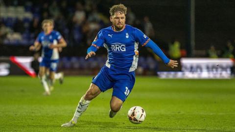 James Norwood with the ball at his feet playing for Oldham during an evening match
