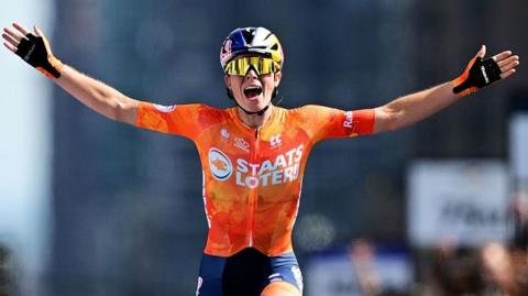 Demi Vollering has her hands outstretched after crossing the finish line