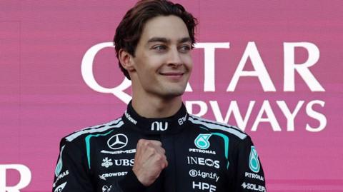 Mercedes' George Russell clenches his right fist in celebration on the podium after winning the Azerbaijan Grand Prix