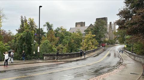 A long road towards the Cornell University campus is seen on a rainy day
