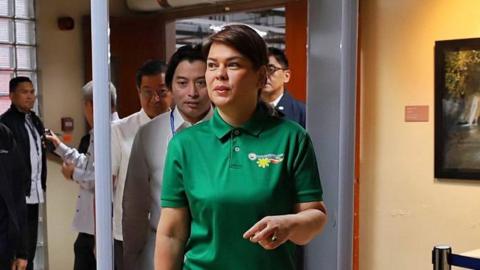 Philippine Vice President Sara Duterte with short cropped hair and green shirt passes through a metal detector at the Senate where her impeachment trial is held
