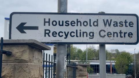 A white sign reading Household Waste Recycling Centre in black text