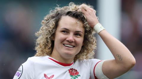 Ellie Kildunne walking on the pitch during a Six Nations match for England with her left hand held on her head in her hair