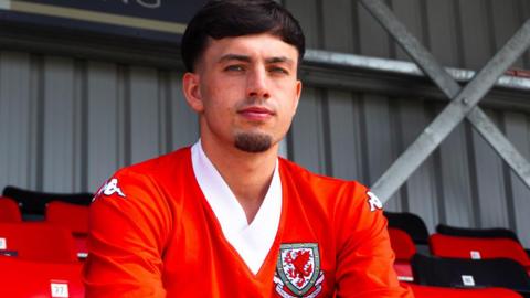 Tom Tweedy sitting in a football stand wearing a Wales football shirt