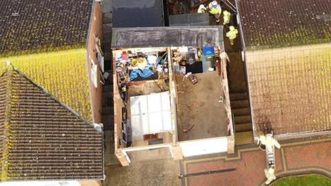 A garage is seen from above. Its roof has ripped off.