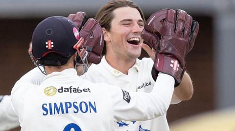 James Coles celebrates a wicket with a high five to wicketkeeper John Simpson