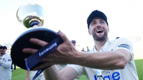 Chris Woakes of Warwickshire lifts the County Championship trophy