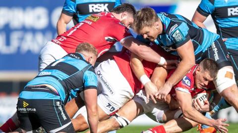 Cardiff and Scarlets players tackle each other