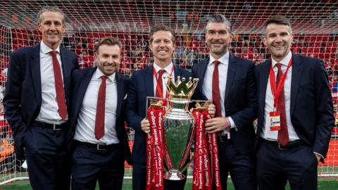 Barry Hunter, Julian Ward, Michael Edwards, Richard Hughes and David Woodfine pose for a photograph with the Premier League trophy after Liverpool won the title in 2025