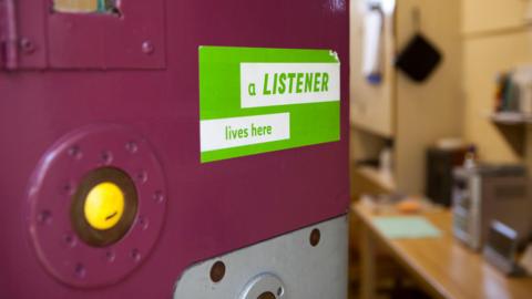 A photo of a prison door with a sign saying 'a Listener lives here'