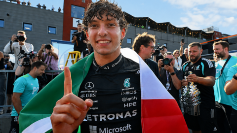 Kimi Antonelli celebrates after winning the Belgium Grand Prix, with an Italian flag draped over his shoulders