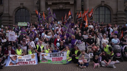 A group of people holding signs which read 'Save Our Stanley's' are gathered outside South Shields Town Hall. Many of them have children either in their arms or in pushchairs.