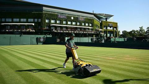A groundskeeper mowing a court at Wimbledon with an Ask Me Anything border around him