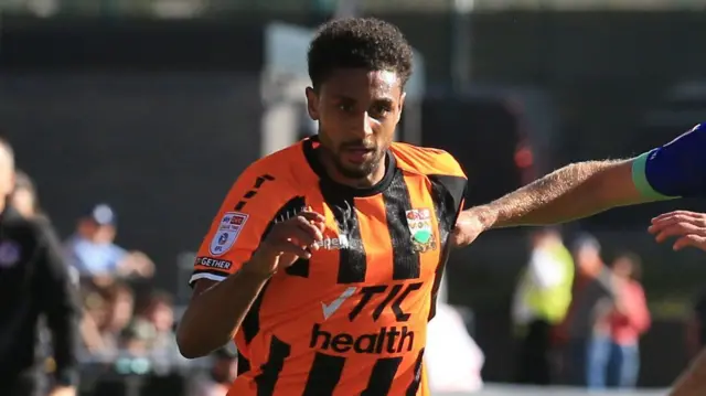Brandon Comley in action for Barnet, wearing their amber and black striped shirt